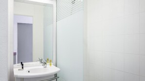 Een badkamer met een wit wastafelmeubel, een spiegel en een douchecabine van glas.