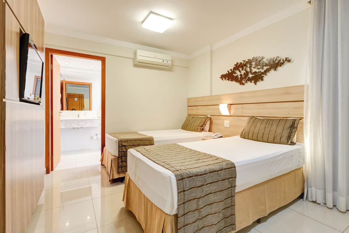 A hotel room with two beds, a bathroom, and a mirror.