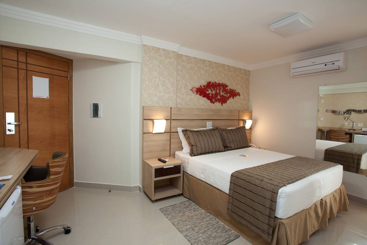 A hotel room with a bed, bedside tables, a desk, and a chair.