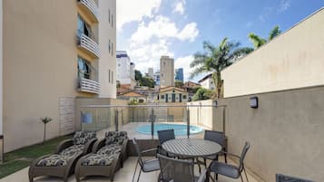 Una piscina al aire libre, sombrillas, sillones reclinables de piscina
