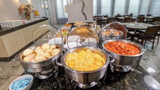 A buffet with various food items, including bread rolls, scrambled eggs, and a red sauce dish. - BH Jaraguá Hotel (Belo Horizonte)
