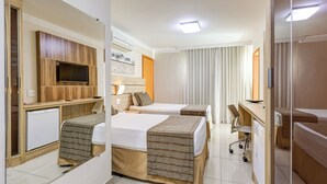 A hotel room with two beds, a desk, a chair, a TV, and a mirror. - BH Jaraguá Hotel (Belo Horizonte)