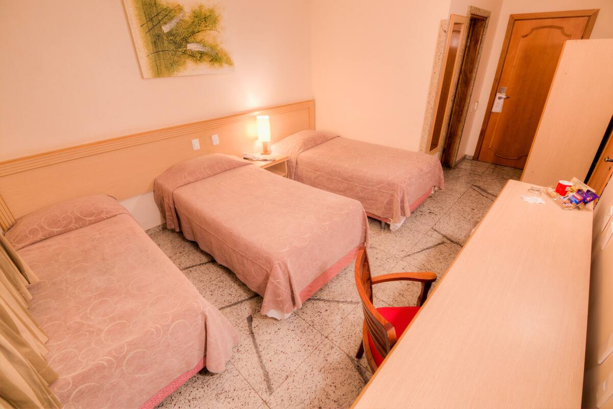 Habitación de hotel con dos camas, un escritorio y una silla.