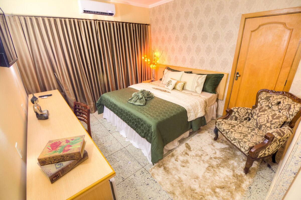 Una habitación de hotel con una cama, una silla, un escritorio y un armario.