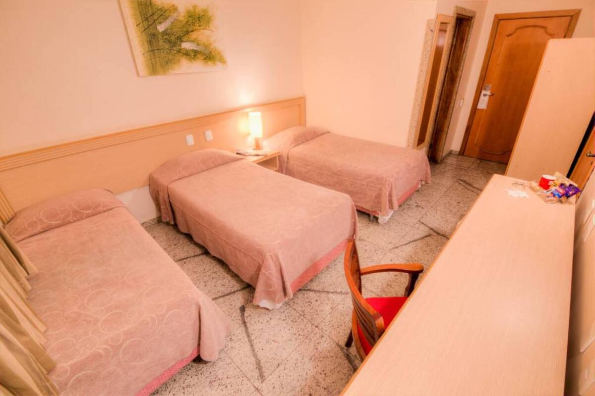 Habitación de hotel con dos camas, un escritorio, una silla y una puerta.