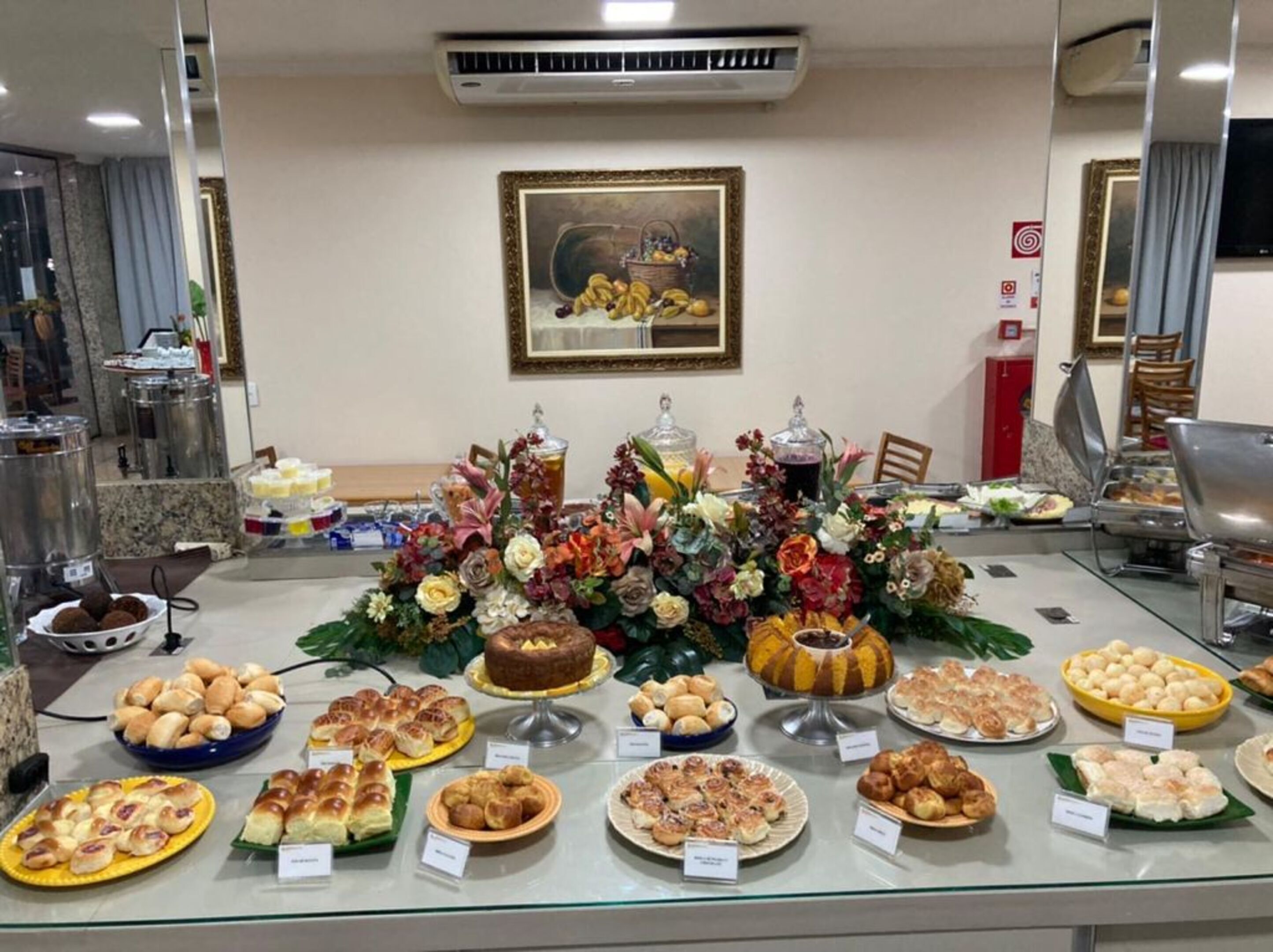 A buffet with various baked goods and a floral centerpiece.