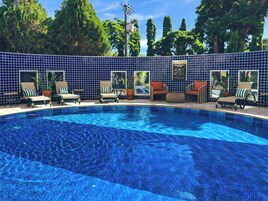 Una piscina al aire libre, sombrillas, sillones reclinables de piscina