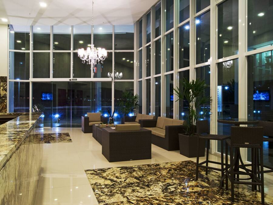 Um hall amplo com uma receção em mármore, áreas de estar confortáveis, grandes janelas e um candelabro.