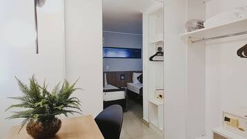Habitación de hotel moderna con una mesa de comedor de madera, una planta en maceta y vista al baño por una puerta abierta.