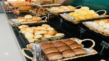 A buffet with various baked goods including bread rolls, muffins, and pastries.