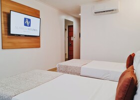 Habitación de hotel con dos camas, un televisor montado en la pared y un equipo de aire acondicionado.