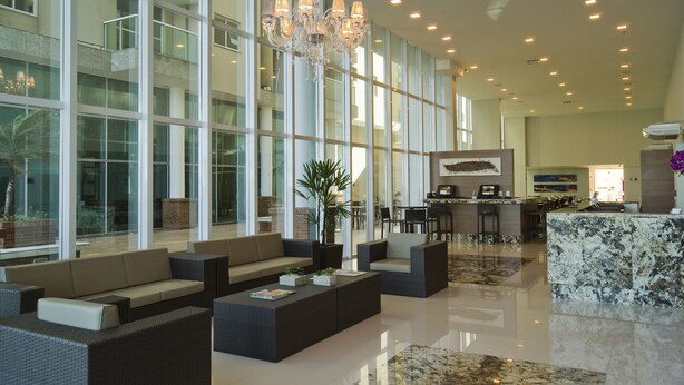 A spacious lobby with high ceilings, large windows, and modern furnishings. - Alameda Vitória Hotel (Vitoria)