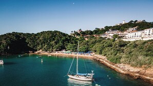 Une zone côtière avec un voilier, une plage et des bâtiments situés sur une colline.