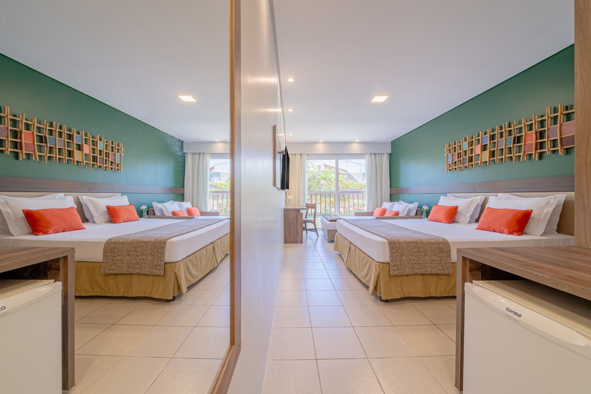 A mirrored hotel room with two beds, a small table, and a refrigerator.