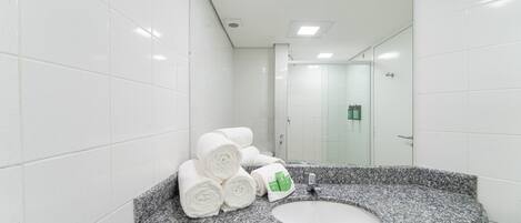 A modern bathroom with white tiled walls, a granite countertop, and a sink.