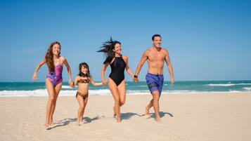 Na praia, espreguiçadeiras, toalhas de praia, prática de vôlei de praia