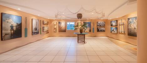A spacious gallery with a tiled floor and walls adorned with various artworks.