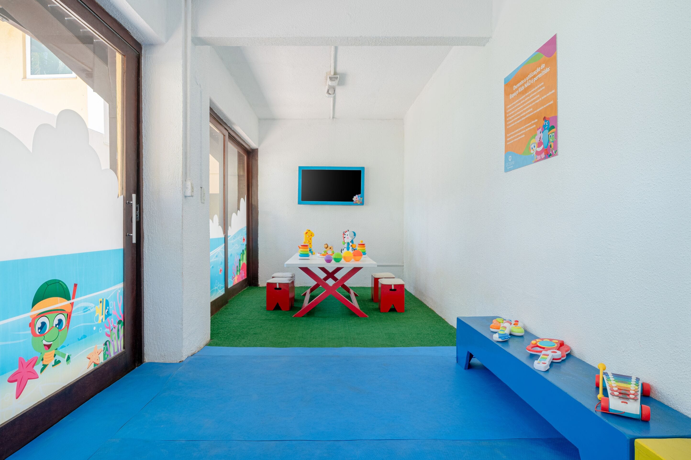 A children's play area with a table, toys, and a mural on the wall.