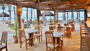 An outdoor restaurant with wooden tables and chairs, potted plants, and a view of the beach and ocean. - Beach Park Oceani Resort (Aquiraz)