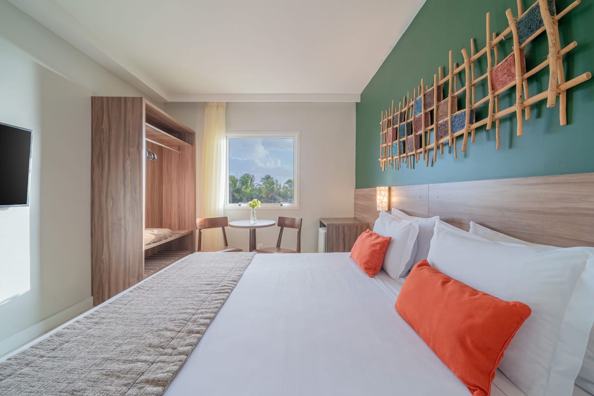 A hotel room with a large bed, a desk, a chair, and a TV.