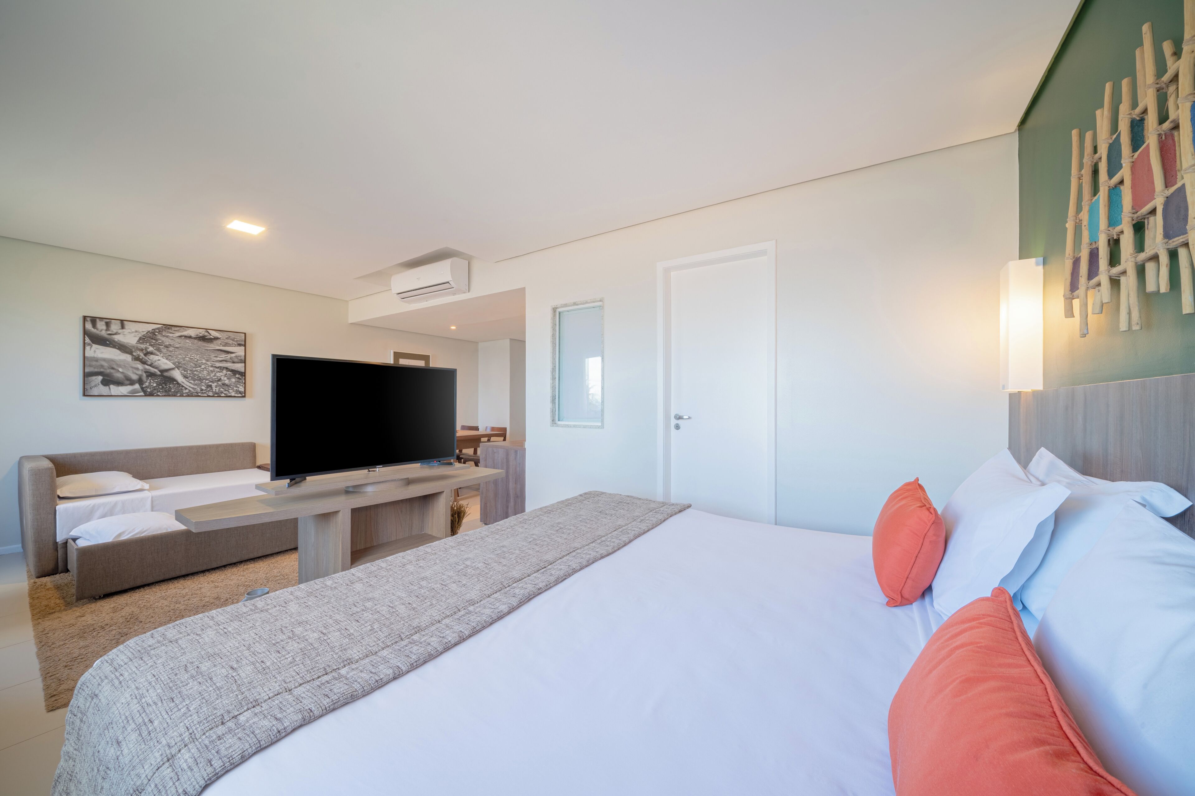 A modern hotel room with a large bed, a flat-screen TV, a sofa, and a desk.