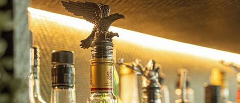 A bar shelf with various liquor bottles, including a prominent bottle with a bird-shaped stopper.