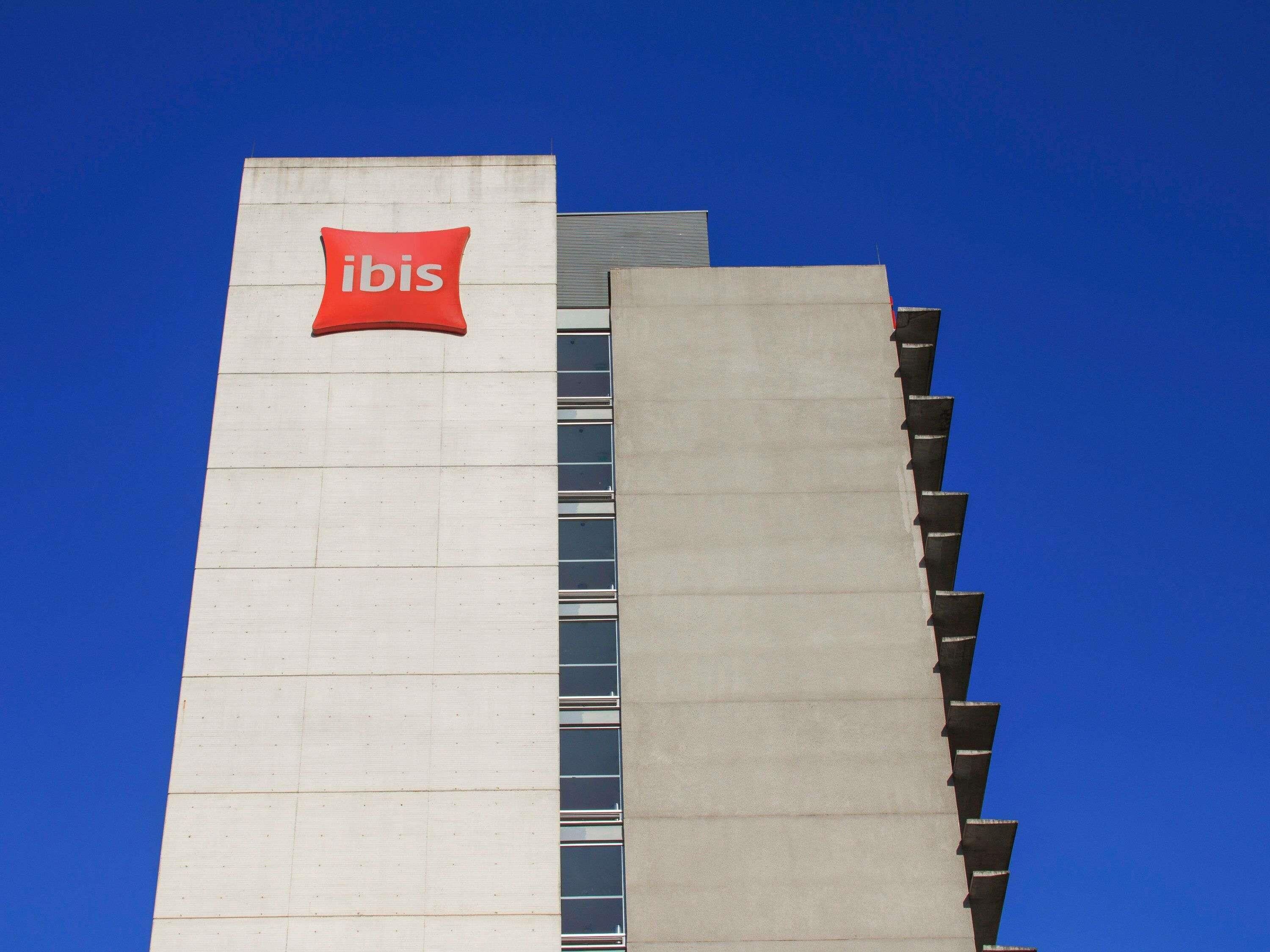 Un grand immeuble sur lequel on peut voir, sur le côté, un logo rouge bien visible représentant un ibis.