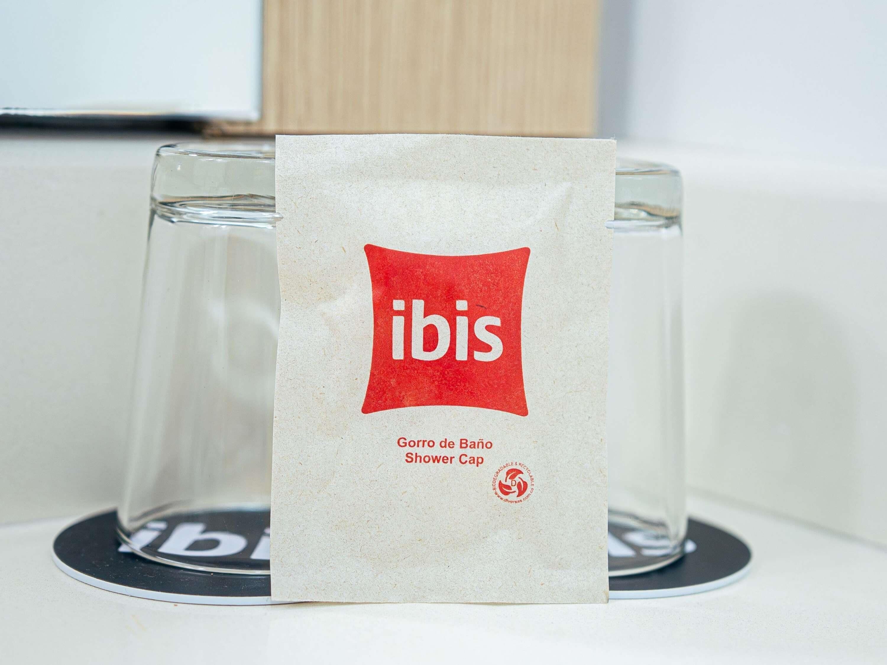 Un gorro de ducha con la etiqueta "ibis" sobre una mesa con dos vasos.