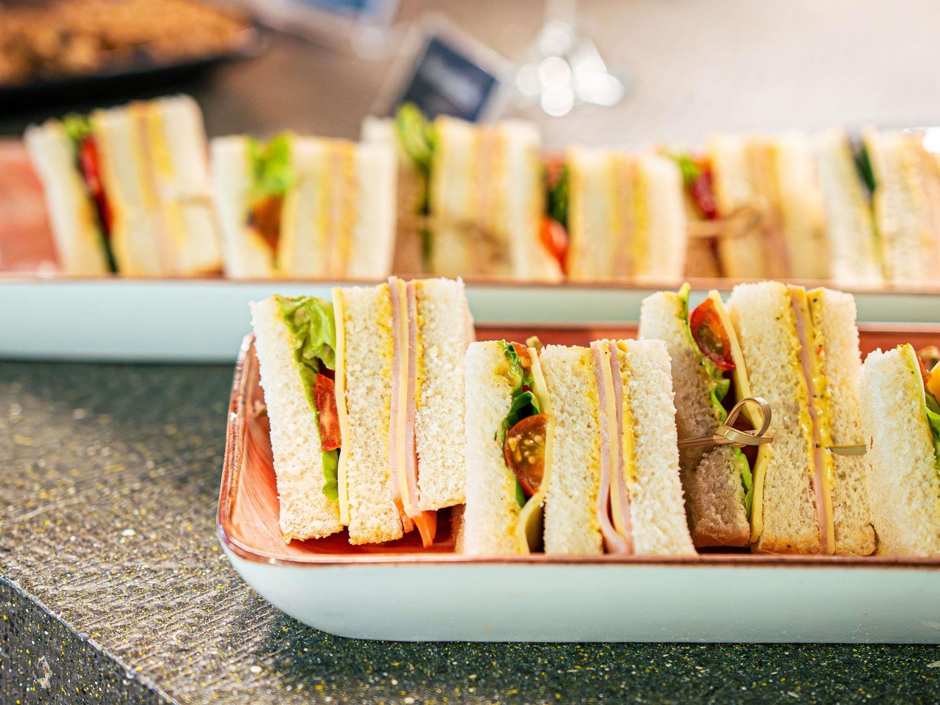 Eine Auswahl an Sandwiches mit sichtbaren Zutaten wie Salat, Tomate und Käse.