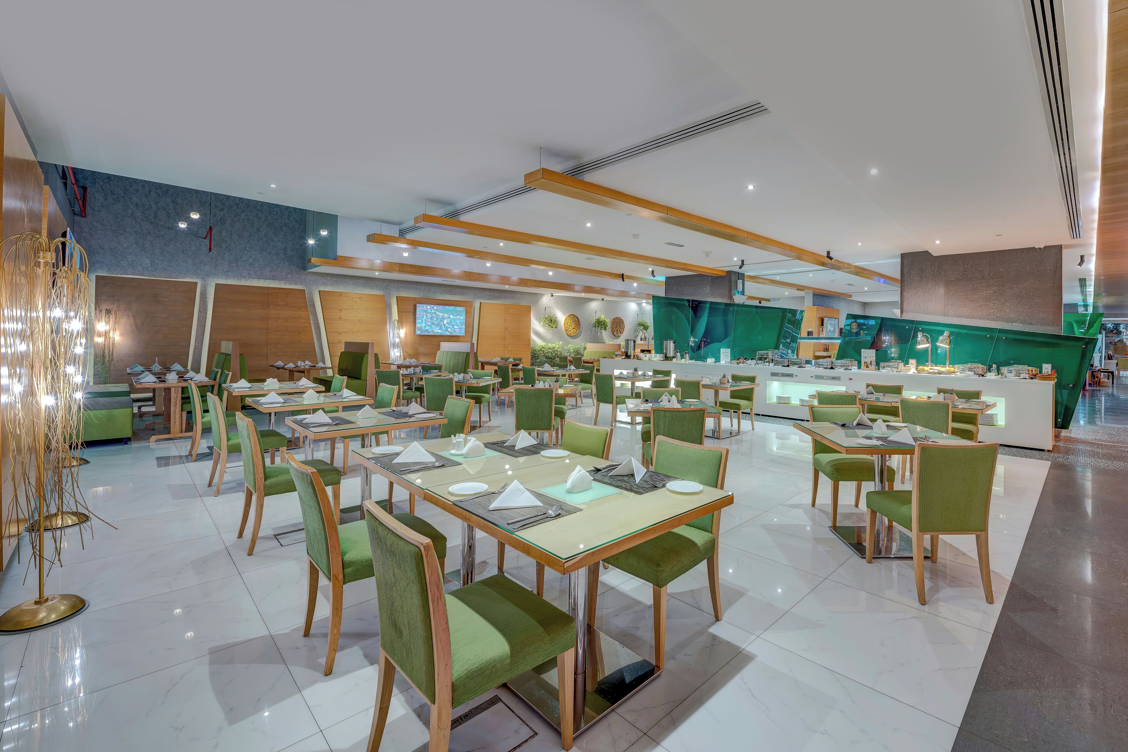 A modern restaurant with multiple dining areas, green upholstered chairs, and a central counter.
