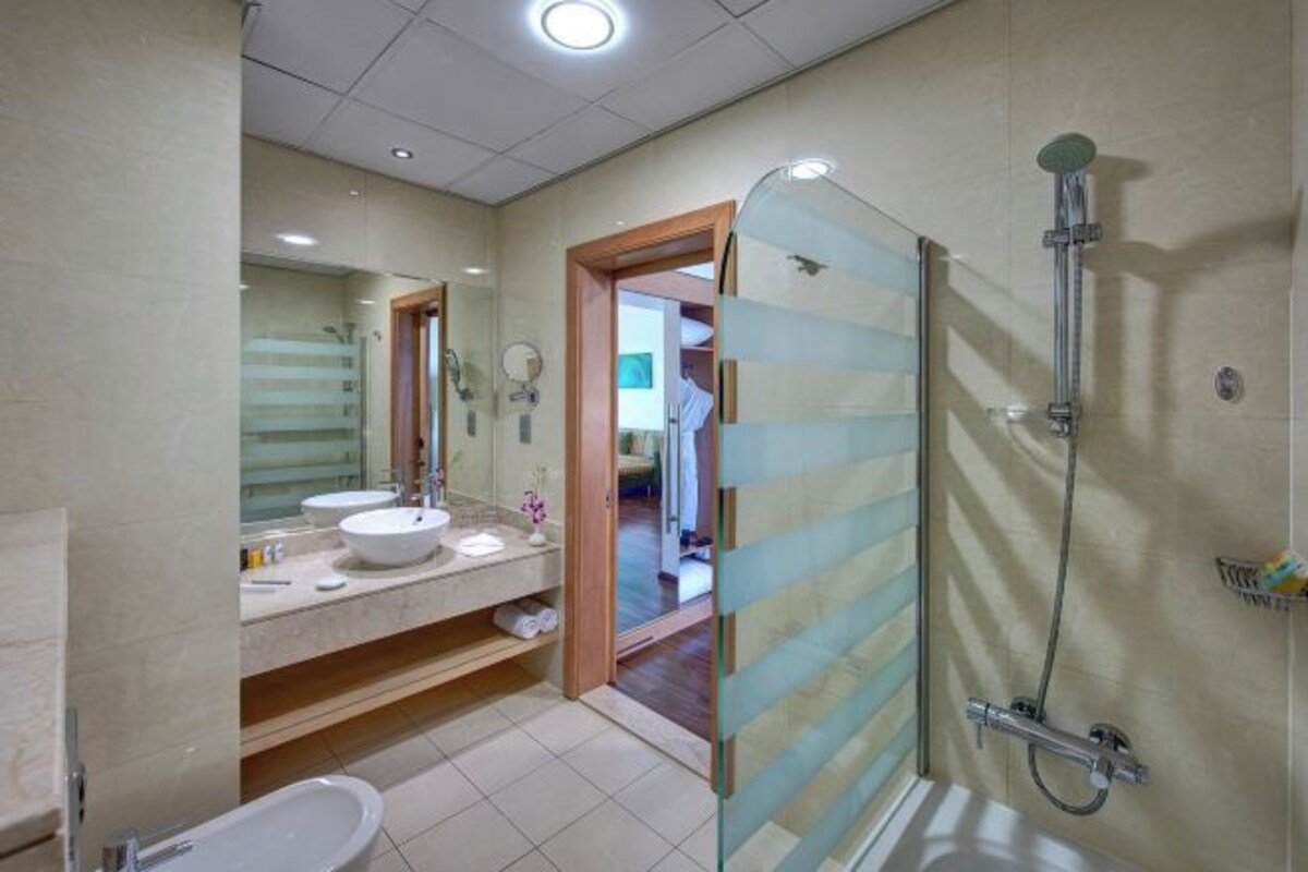 A modern bathroom with a glass shower enclosure, a sink with a mirror, and a toilet.