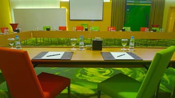 A conference room with a long table, chairs, water bottles, glasses, and a projector screen.