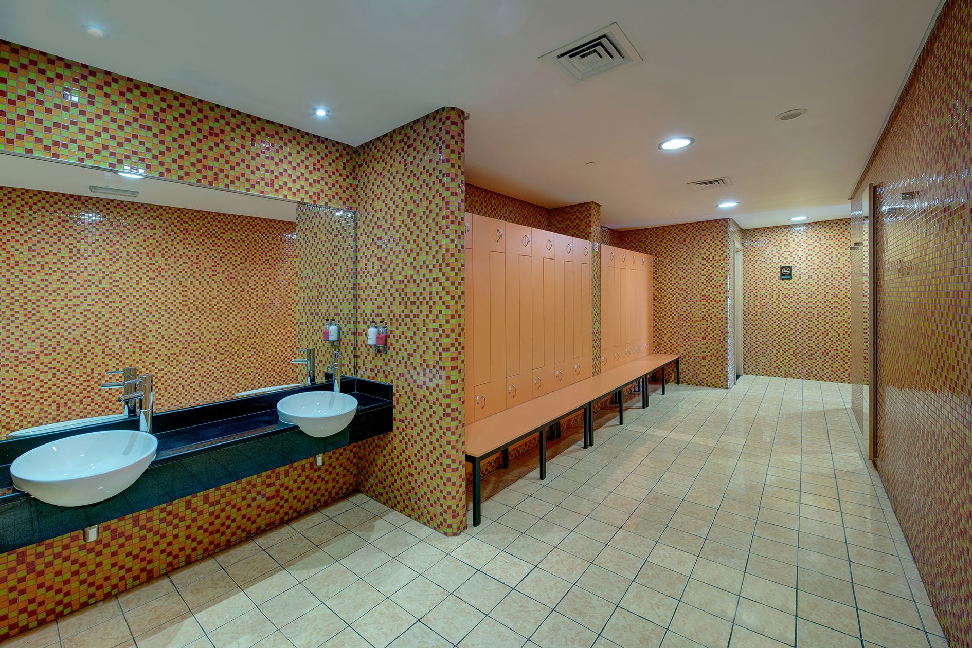 A public restroom with two sinks, a mirror, and a row of lockers.