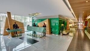 Eine moderne Hotelhalle mit einer Rezeption, einem Bereich für die Gästebetreuung und einer Lounge mit Sitzgelegenheiten.