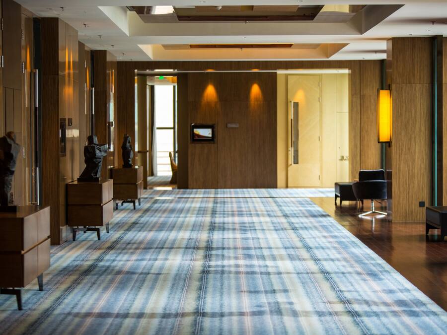 Un hall d’hôtel comprenant un comptoir d’enregistrement, un espace salon et un grand sol recouvert de moquette.