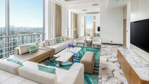 Un salon moderne doté d’un grand téléviseur, de sièges confortables et offrant une vue sur la ville.
