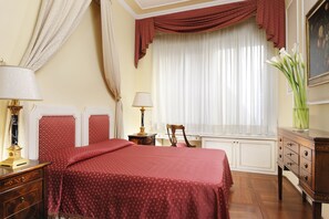 A bedroom with a large bed, two bedside tables, a dresser, a chair, and a window with curtains. - Art and Luxury Apartments (Florence)