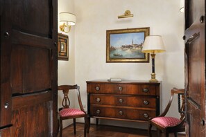 A wooden dresser with drawers, a framed painting above it, and two chairs with red cushions. - Art and Luxury Apartments (Florence)