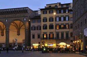 A historic square with a prominent archway and a building with a restaurant sign. - Art and Luxury Apartments (Florence)