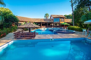 A swimming pool with a wooden deck, a gazebo, and a building with a tiled roof. - Hotel Pousada Arizona (Bonito)