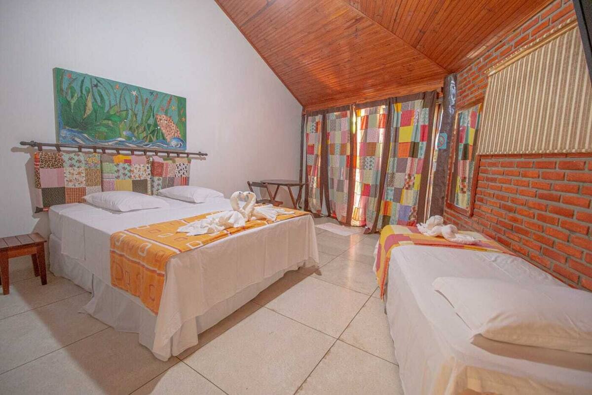 A room with two beds, a painting, and a brick wall.