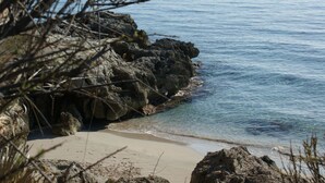 Une côte rocheuse bordée d’une eau claire et d’une plage de sable.