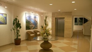 Un hall d’entrée avec une table à plateau de verre, des plantes en pot, une carte accrochée au mur et un escalier.