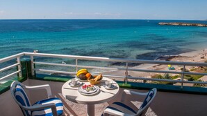 Un balcon avec une table préparée pour le petit-déjeuner, donnant sur une plage et la mer.