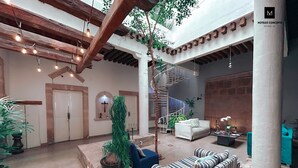 Un vaste espace intérieur doté d’un haut plafond, d’un escalier et d’un coin salon avec des coussins à rayures.