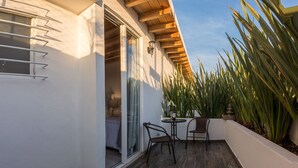 Une terrasse avec un plancher en bois, une table, des chaises et une plante en pot.