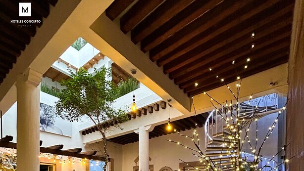 Un espace intérieur spacieux au design moderne, comprenant un canapé vert, un escalier et un éclairage décoratif.