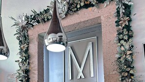 Un comptoir d’accueil d’hôtel orné d’un grand logo en forme de « M », d’une enseigne indiquant « HOTELES CONCEPTO » et d’un drapeau.