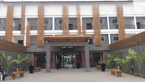 A hotel entrance with a modern design, featuring vertical wooden slats and a sign that reads "SUNU HOTEL". - Sunu Hotel (Serrekunda)