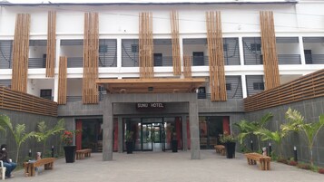 A hotel entrance with a modern design, featuring vertical wooden slats and a sign that reads "SUNU HOTEL".
